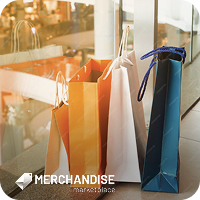 Shopping bags of various colors and sizes are placed on a tiled floor near a glass window. The background shows a blurred view of a store interior with warm lighting.