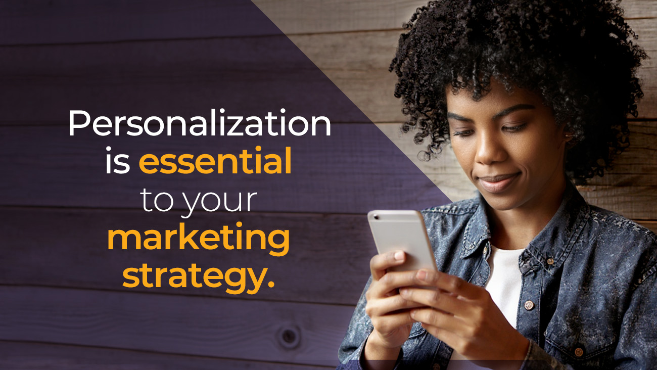 A woman with curly hair looks at her phone and smiles. Text on the left says: Personalization is essential to your marketing strategy. The words essential and marketing strategy are highlighted in yellow.