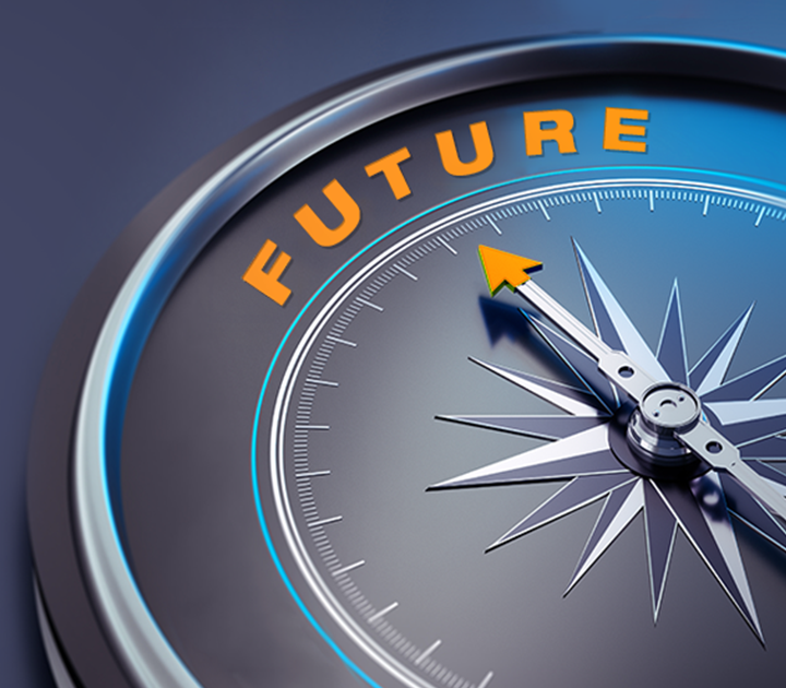 Close-up of a silver compass with a blue edge, featuring a needle pointing towards the word FUTURE in bright orange letters. The compass design implies direction or guidance towards future possibilities.