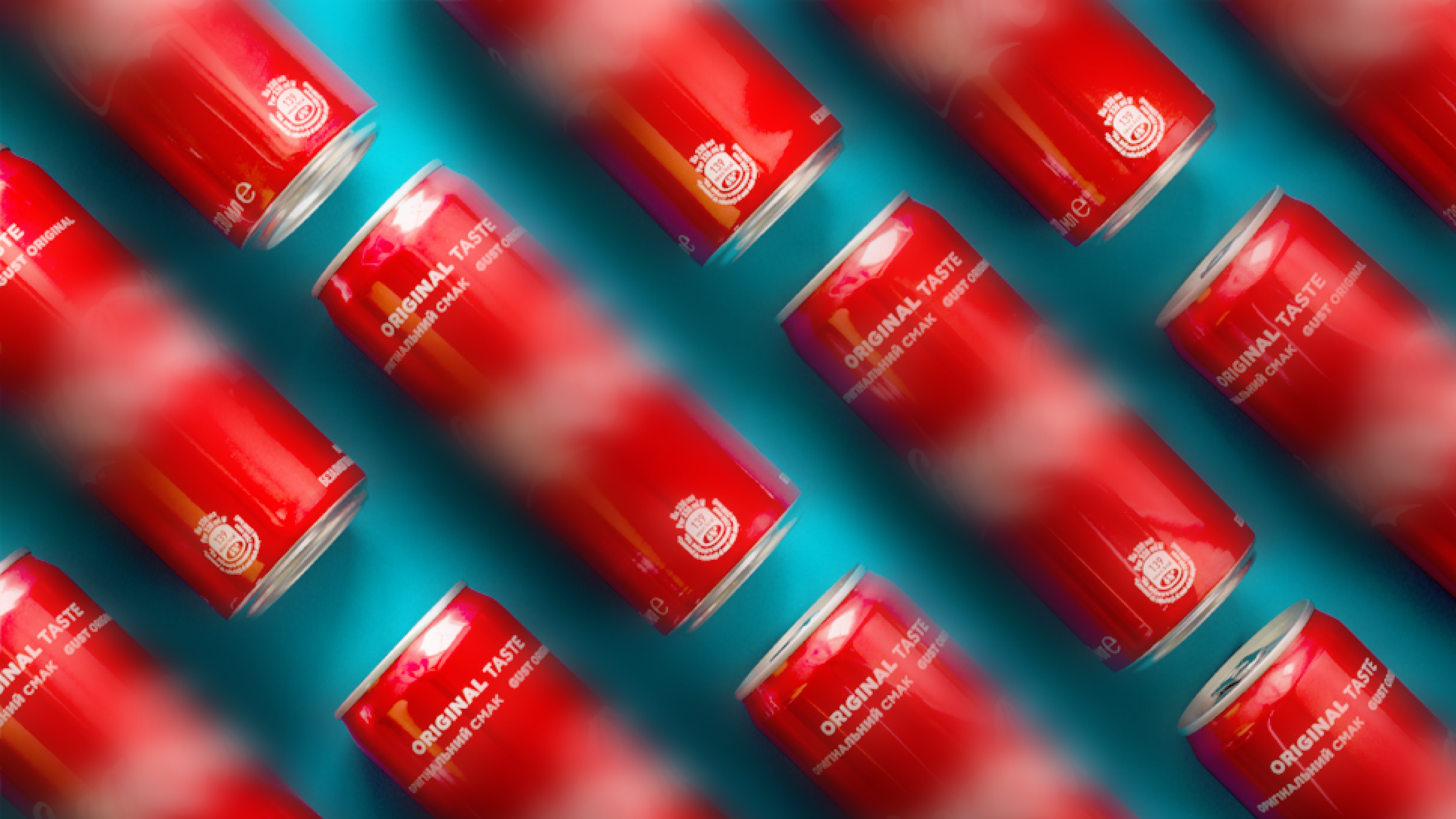 Diagonal rows of red soda cans with the text Original Taste and a classic white logo are placed against a bright aqua background. Some cans are in focus, while others appear blurred.